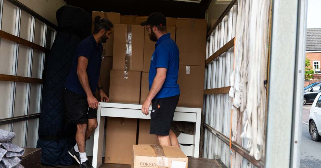 Two Simply Moving crew members loading boxes into a removal van